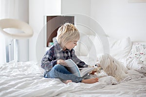 Cute toddler child and puppy dog  lying on the bed  reading book together  family time