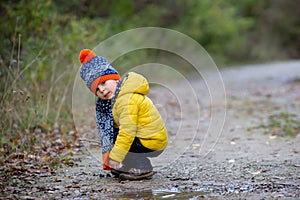 Cute toddler child with yellow jacket, running in autumn park, playing and jumping