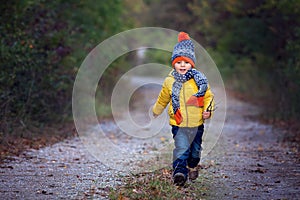 Cute toddler child with yellow jacket, running in autumn park, playing and jumping