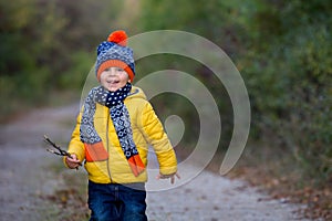 Cute toddler child with yellow jacket, running in autumn park, playing and jumping