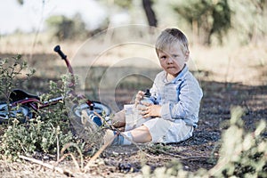 Cute toddler drinking water next to bicycle in the nature photo