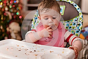 cute toddler eating food and candy in front of a christmas tree