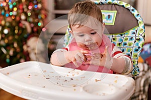 cute toddler eating food and candy in front of a christmas tree