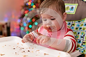 cute toddler eating food and candy in front of a christmas tree