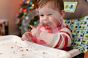 cute toddler eating food and candy in front of a christmas tree