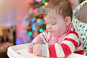 cute toddler eating food and candy in front of a christmas tree