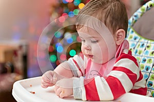 cute toddler eating food and candy in front of a christmas tree