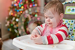 cute toddler eating food and candy in front of a christmas tree