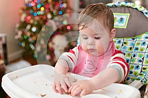 cute toddler eating food and candy in front of a christmas tree