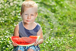 Cute toddler eating a slice of watermelon