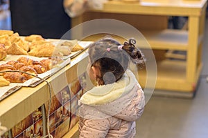 Cute toddler girl in bakery store.