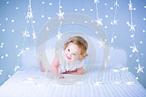 Cute toddler girl with curly hair between Christmas lights