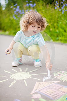 Cute toddler girl drawing with piece of color chalk.