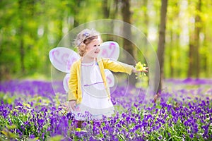 Cute toddler girl in fairy costume in bluebell forest