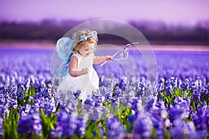 Cute toddler girl in fairy costume in a flower field