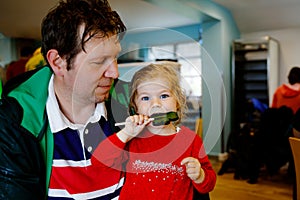 Cute toddler girl and father with cloverleaf lollipop in Irish pub or cafe. Child and dad, young man resting with