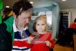 Cute toddler girl and father with cloverleaf lollipop in Irish pub or cafe. Child and dad, young man resting with