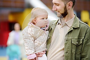 Cute toddler girl having fun on outdoor playground. Young father playing with his little daughter. Spring/summer/autumn active