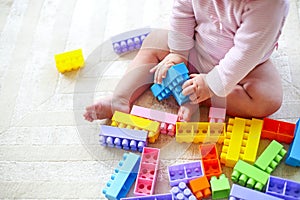 Cute toddler girl having fun with toy blocks sitting on the carp