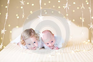 Cute toddler girl and her little newborn baby brother with warm soft lights