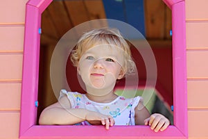 Cute toddler girl hiding in playhouse at playground