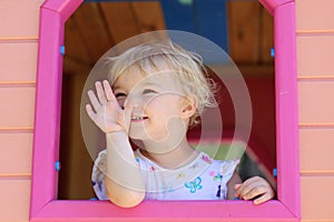 Cute toddler girl hiding in playhouse at playground