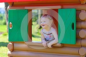 Cute toddler girl hiding in playhouse at playground