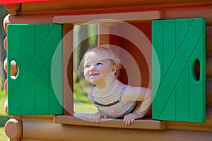 Cute toddler girl hiding in playhouse at playground