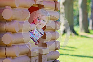 Cute toddler girl hiding in playhouse at playground