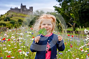 Cute toddler girl with Irish cloverleaf lollipop with Rock of Cashel castle on background. Happy healthy child on flower
