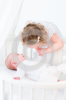 Cute toddler girl kissing the hand of her baby brother