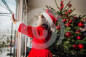 Cute toddler girl looking at the window at Christmas time