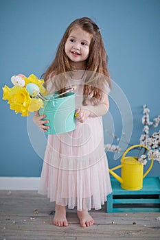 Cute toddler girl in pink dress holding bouquet of daffodills