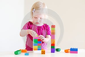 Cute toddler girl plaing with colorful blocks