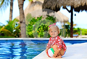 Cute toddler girl playing with ball in swimming