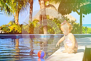 Cute toddler girl playing with ball in swimming
