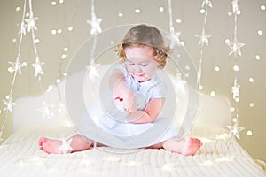 Cute toddler girl playing with her toy bear between soft lights in star shape