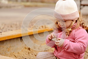 Cute toddler girl playing in sand on outdoor playground. Beautiful baby having fun on sunny warm summer day