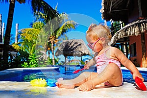 Cute toddler girl playing in swimming pool at the