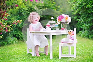 Cute toddler girl playing tea party with a doll