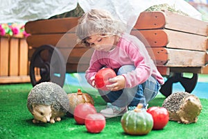 Cute toddler girl playing with toy hedgehog.