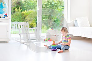 Cute toddler girl playing in a white room with big