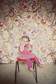 Cute toddler girl sitting on a red chair