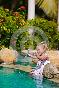 Cute toddler girl splashing in swimming pool