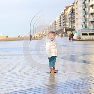 Cute toddler girl walking on winter promenade