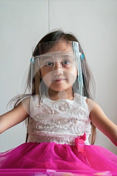 A cute toddler girl wearing the face protection shield. A safety face shield corona mask during Covid-19 pandemic