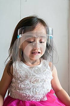 A cute toddler girl wearing the face protection shield. A safety face shield corona mask during Covid-19 pandemic