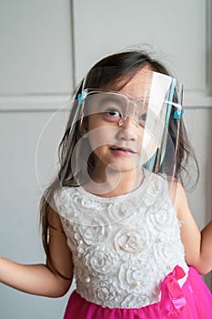 A cute toddler girl wearing the face protection shield. A safety face shield corona mask during Covid-19 pandemic