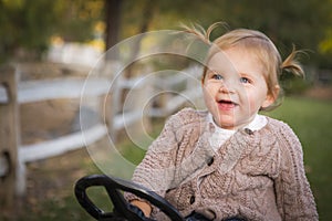 Cute Toddler Laughing and Playing on Toy Tractor Outside