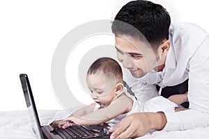 Cute toddler playing laptop with his dad